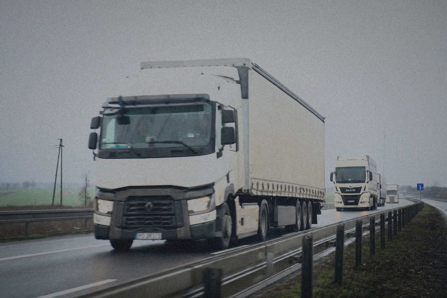 Ciężarówki z naczepami jadące autostradą w pochmurny dzień